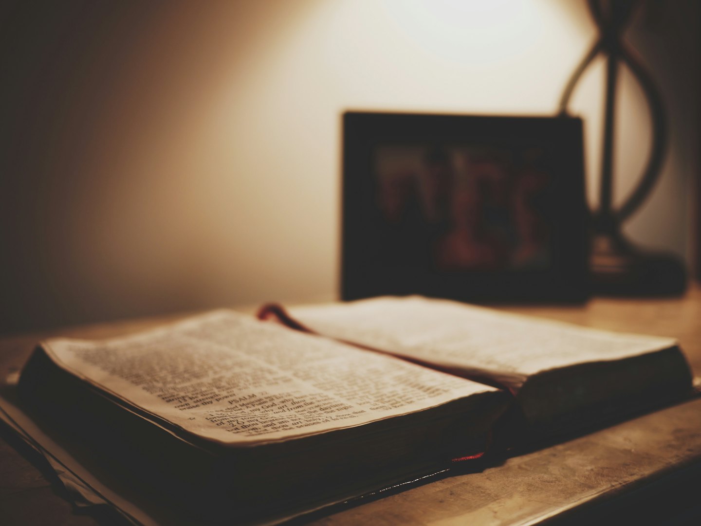 Open Bible resting on a wooden table with soft light.