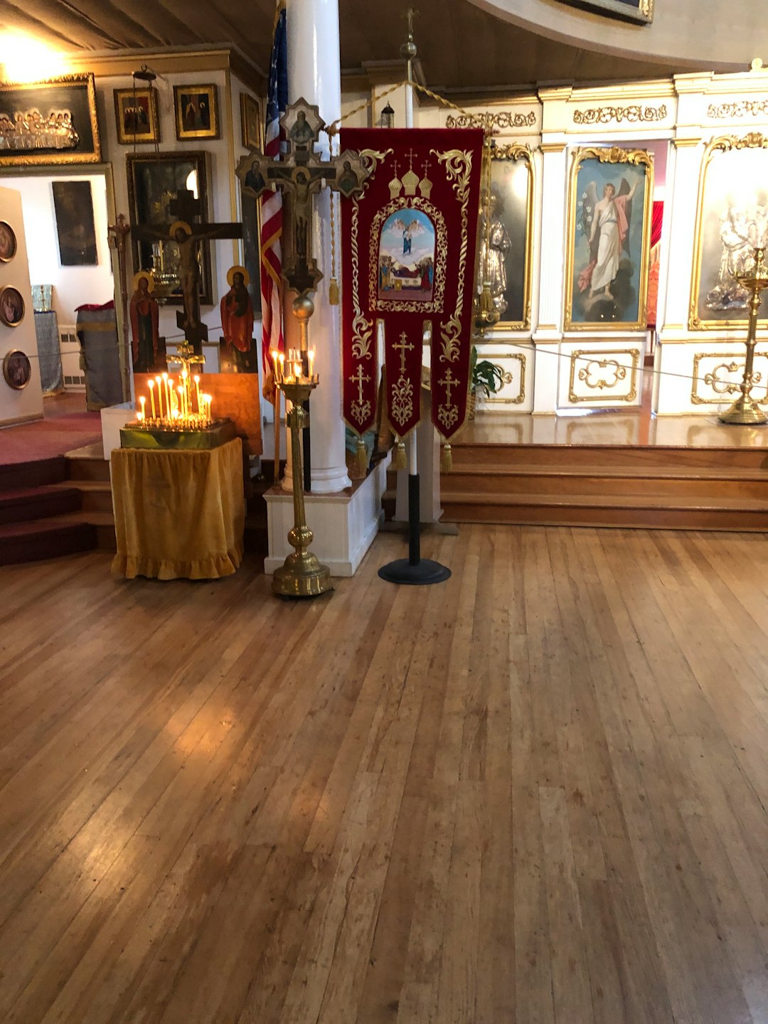 Lit candles and a brass crucifix stand inside an ornate church.