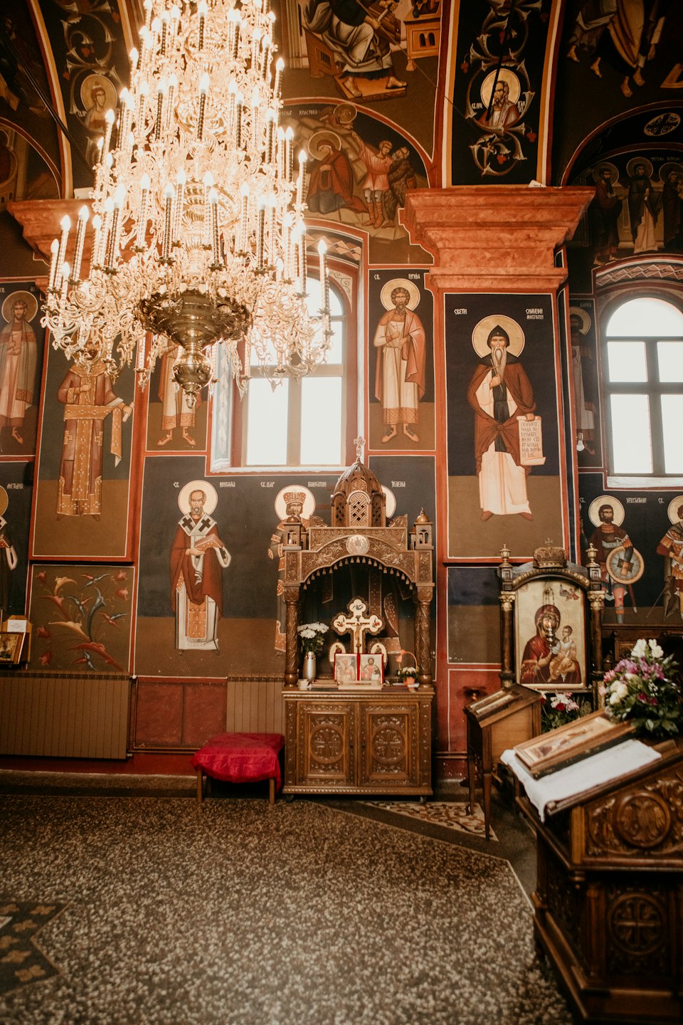 A golden chandelier hangs inside an ornate Orthodox church.