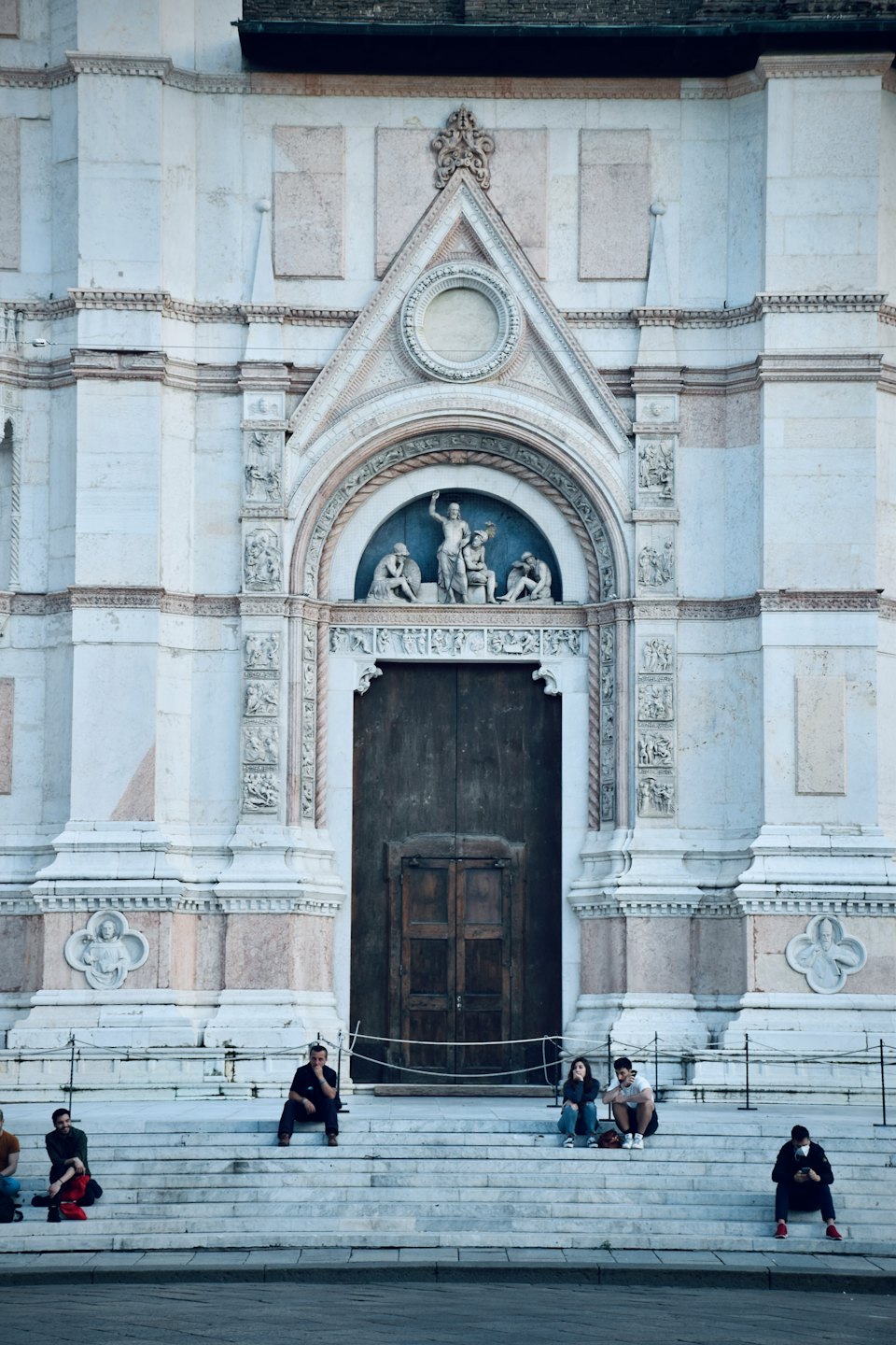 Diverse young adults relax on stone steps outside a grand church.