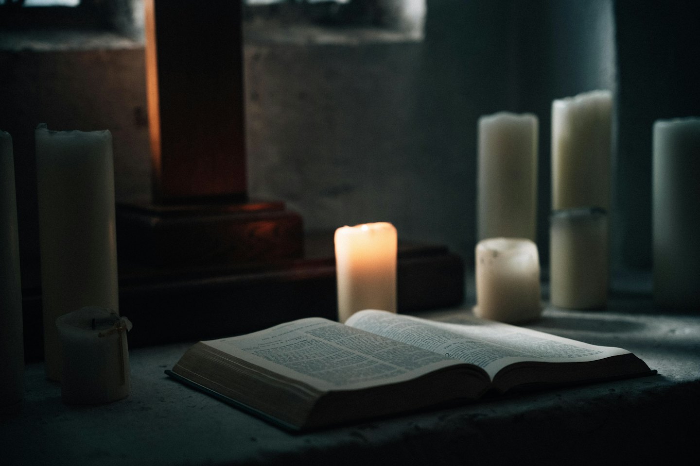 Open book on stone with a lit candle.