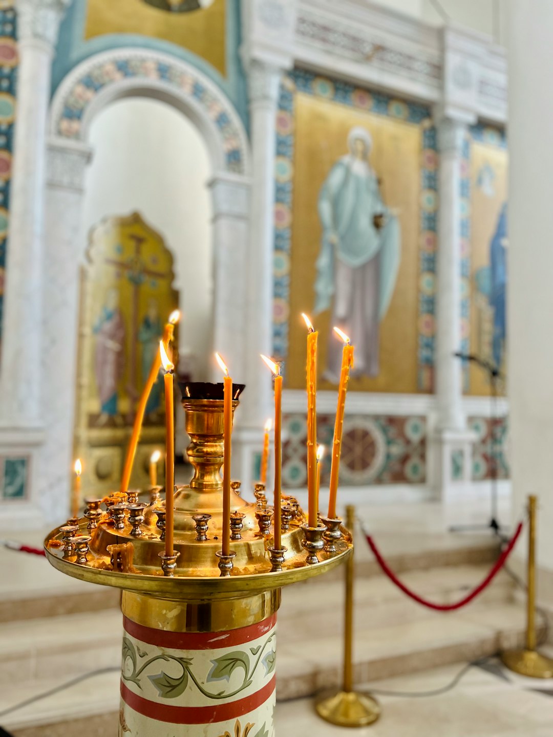 Thin yellow candles burn brightly on a brass candle stand.