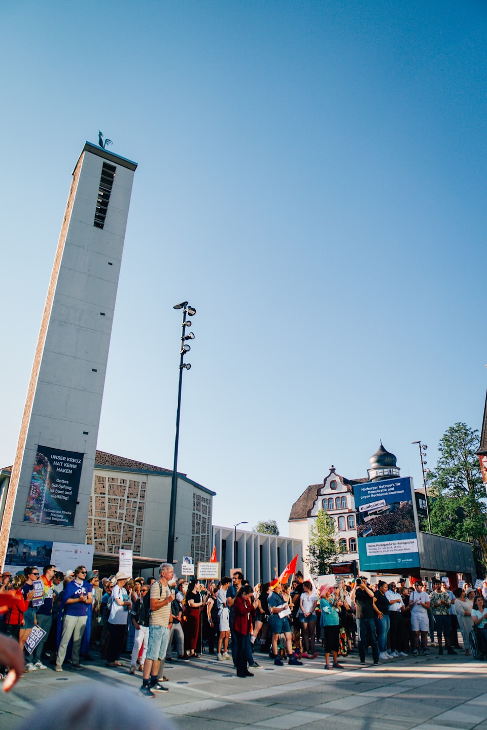 Diverse crowd gathered in a sunny city square during an outdoor event.